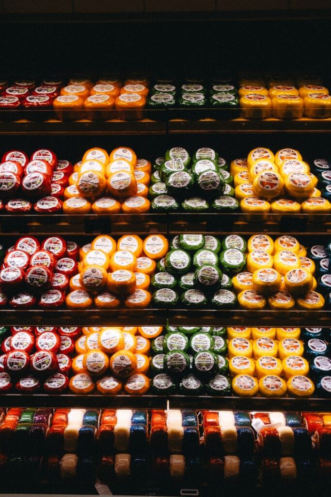 Colorful display of diverse cheese selection on shelves in an Amsterdam shop.