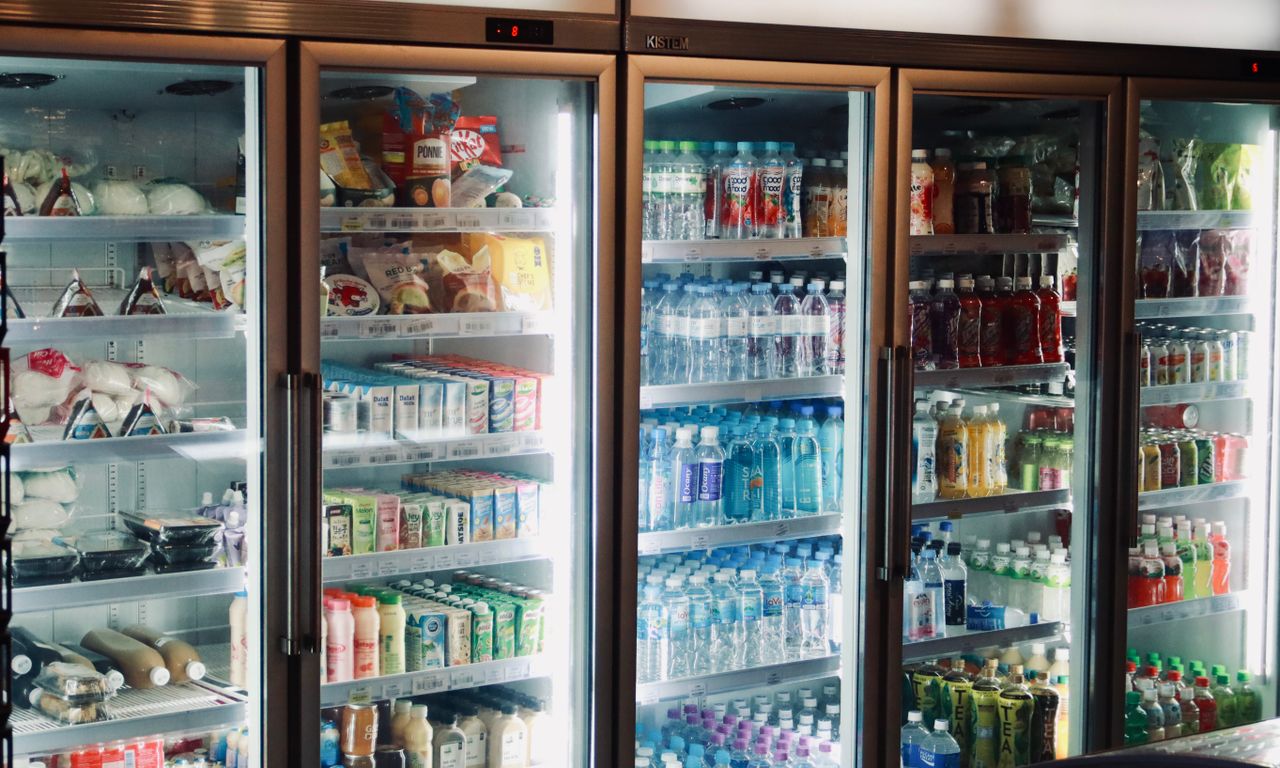Refrigerator display with various beverages and snacks in a store environment.