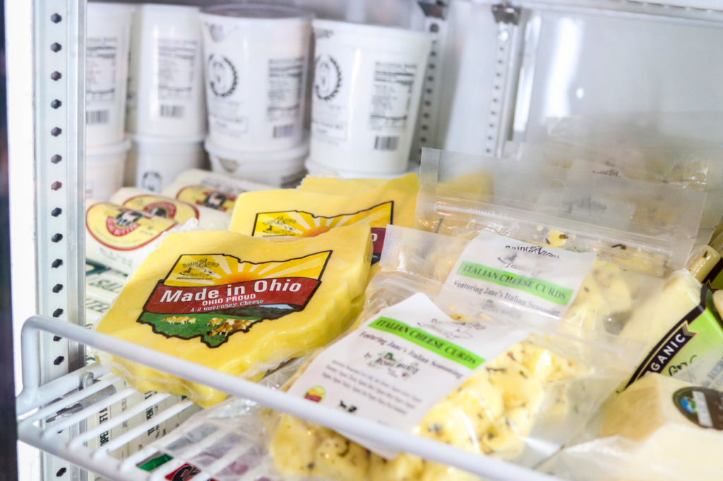 A variety of fresh Ohio cheeses displayed in a store refrigerator, showcasing local produce.