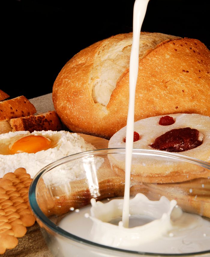 Close-up of fresh bread, milk, and baking ingredients on a table, showcasing a homemade touch.